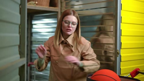 Jeune femme à lunettes mettant ses effets personnels sur l'étagère supérieure dans un casier de rangement à l'intérieur