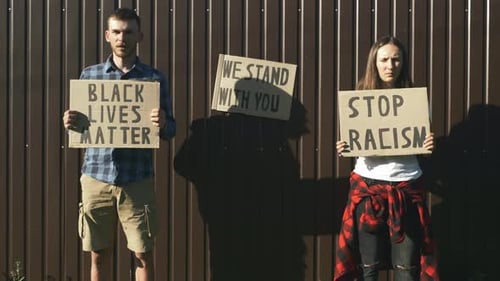 Young Adults Holding Protest Signs on Urban Street