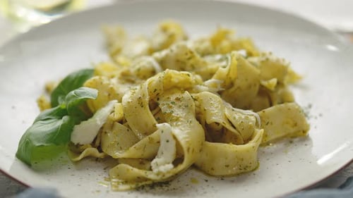 Close Up of Fresh Cooked Tagliatelle Pasta with Green Pesto and Herbs
