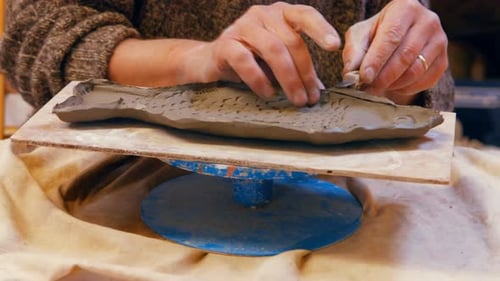 Hands Shaping Clay Fish on Potter's Wheel