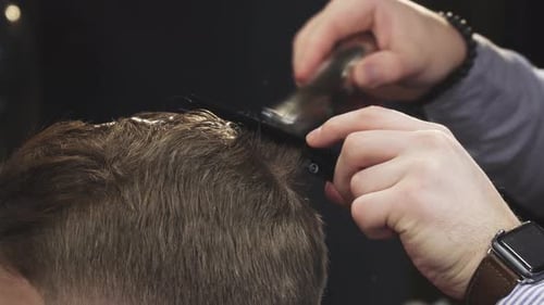 Barbier schneidet Haare seines Kunden mit einem Trimmer