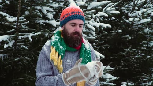 Man Warms Hands in Snowy Evergreen Forest