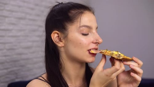 Young Woman Eating Slice of Delicious Pizza