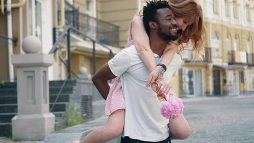 Happy Young Woman Having Fun Rides on the Back of Her Boyfriend in the City