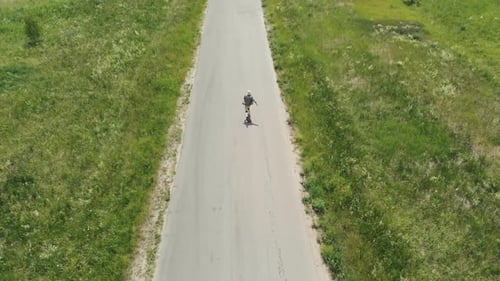 Man Rides at Straight Road on Longboard at Sunset Time Aerial . The Guy Rides a Longboard on the Way