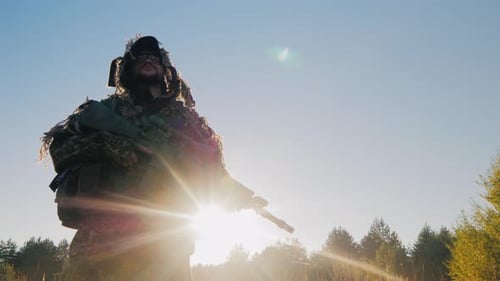 Camouflaged Soldier Holds Rifle at Sunrise
