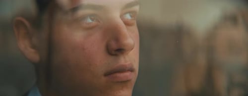 Young european man looking out of the window, daydreaming