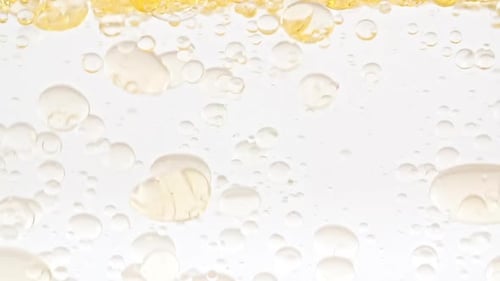 Bubbles Floating in Yellow Liquid on White