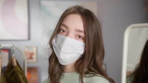 Young Woman Wearing Protective Mask Looks at Camera