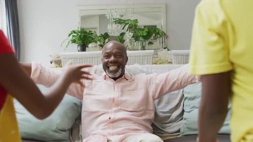 Grandfather Embraced by Happy Children on Couch