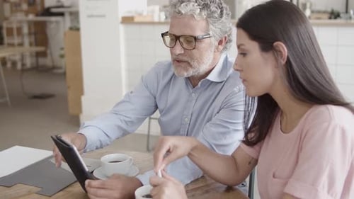 Professionals Collaborate Over Tablet at Cafe Table