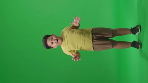 Cuerpo completo de un niño asiático sorprendido sorprende mientras dice guau sobre fondo de pantalla verde