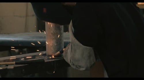 Welder welding metal parts in a workshop