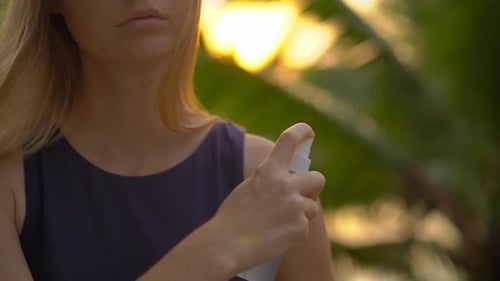 Woman Sprays Bug Repellent Outdoors in Tropical Setting