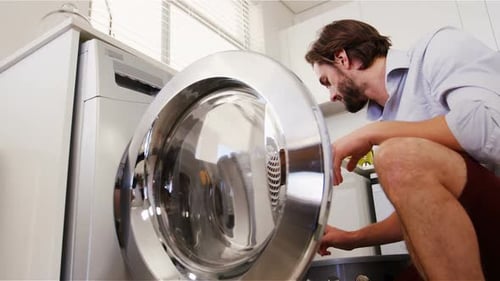 Young Adult Loads Washing Machine in Modern Kitchen