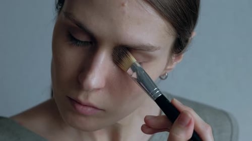 Young Adult Woman Applying Makeup with Brush Close Up