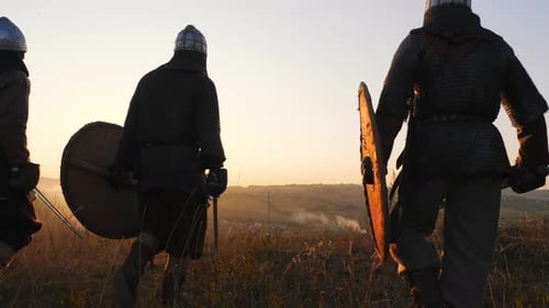 Silhouettes of Viking Warriors Gather and Stop in the Field and Watch the Beautiful Sunset