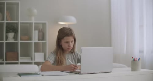 Girl Studying at Desk With Laptop Writing Notes