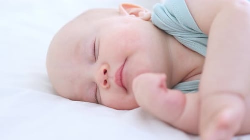 Infant Sleeping Soundly on White Blanket
