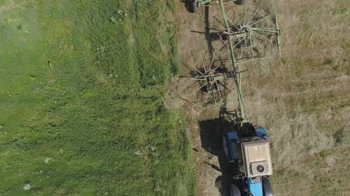 Trator com Rake Tedders no campo da fazenda