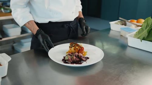 The chef gives the finished dish filet mignon and ratatouille in the restaurant kitchen