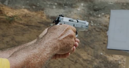 Movimiento lento de una pistola de mano disparando en un campo de tiro con el cartucho volando
