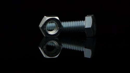 Bolt and Nut Lie Beside and Rotate on Black Stand