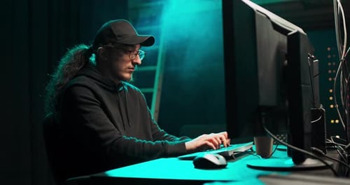 Man Typing on Computer in Dark Tech Environment