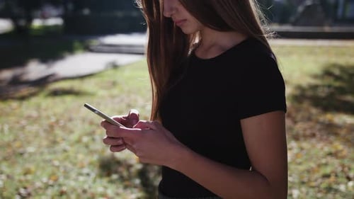 An Attractive Young Lady Using a Phone in Town. Medium Shot