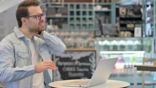 Young Adult Man Using Laptop Experiencing Neck Pain