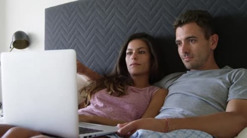 Cute couple using laptop in bedroom at home 4k
