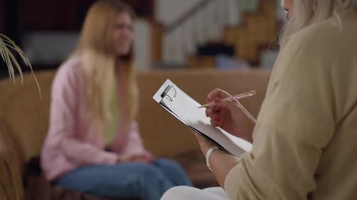 Tir par-dessus l'épaule d'un psychothérapeute expert avec un stylo et de la paperasse posant des questions