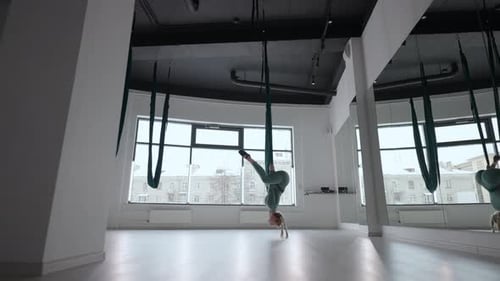 Attractive Fitness Trainer Doing Antigravity Aerial Flying Yoga Exercises in Green Hammock