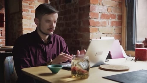Portrait of an Attractive Young Man Working on His Laptop at the Cafe