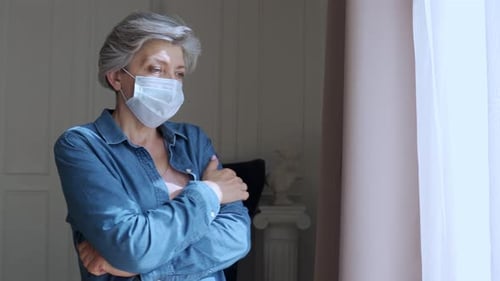 Senior Woman Wearing a Mask Looking Out Window