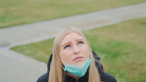 Blonde Woman Puts On Face Mask Outdoors
