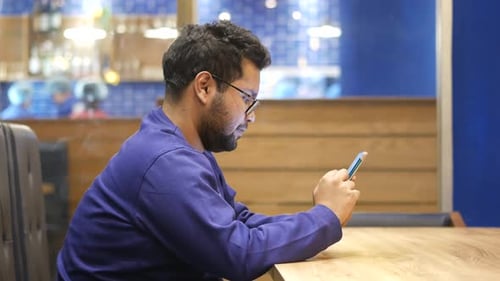 Vue latérale d'un jeune homme utilisant un téléphone intelligent au café