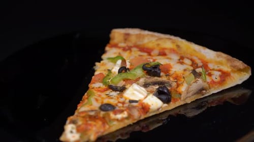 Vegetarian Pizza Slice Rotating on Black Surface