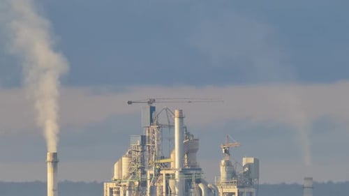 Zeitraffer eines Zementwerks mit hoher Fabrikstruktur und Turmdrehkranen im industriellen Produktionsbereich