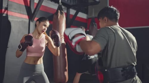 Woman Boxing with Trainer in Gym Setting