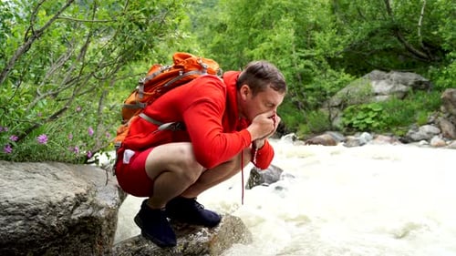 Viajero masculino se lava la cara con agua de montaña