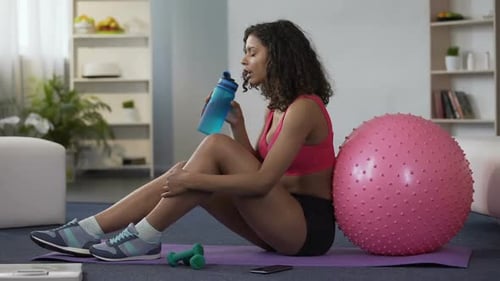 Woman Drinking Water After Exercise at Home