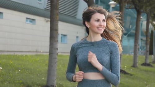 Portrait of Young and Fit Woman Running and Jogging Alone on the Empty Street in