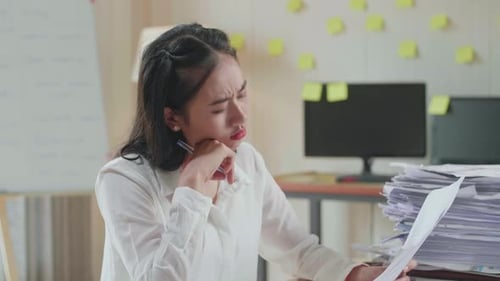 Close Up Of Asian Woman Thinking And Looking At Paper Then Raising Index Finger While Working