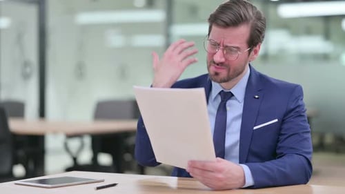 Distressed Man at Desk Reads Documents