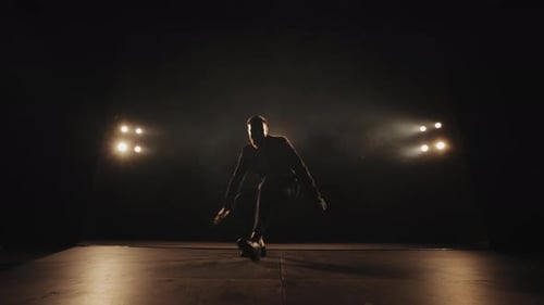 Energetic Man Breakdancing on Dark Stage Under Spotlights