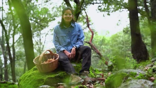 Woman attentively looking at camera with mushroom in woods