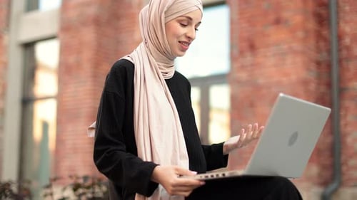 Woman With Headscarf Uses Laptop Outside