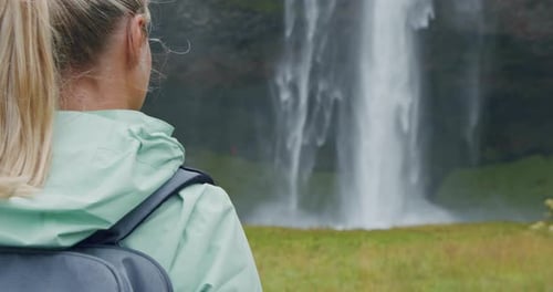 Nahaufnahme einer Reisenden zurück mit Rucksack und Blick auf den schönen Seljalandsfoss Wasserfall Island