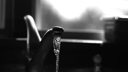 Wasser fließt in Ultrazeitlupe 1500 fps aus einem Wasserhahn auf einer reflektierenden Oberfläche - WASSERHAHN